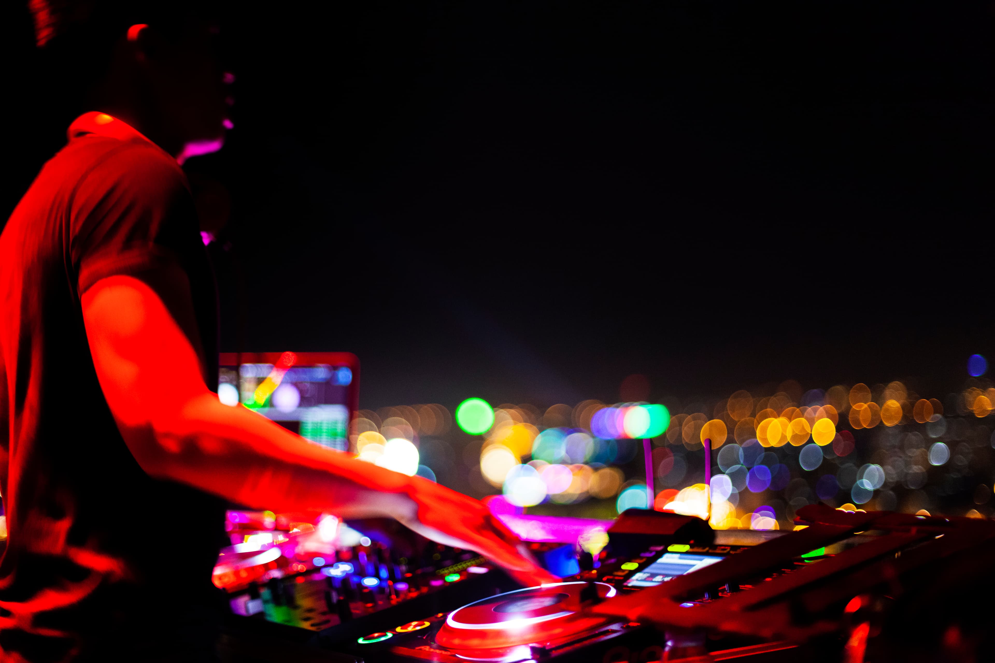 DJ am Mischpult vor nächtlichen Lichtern