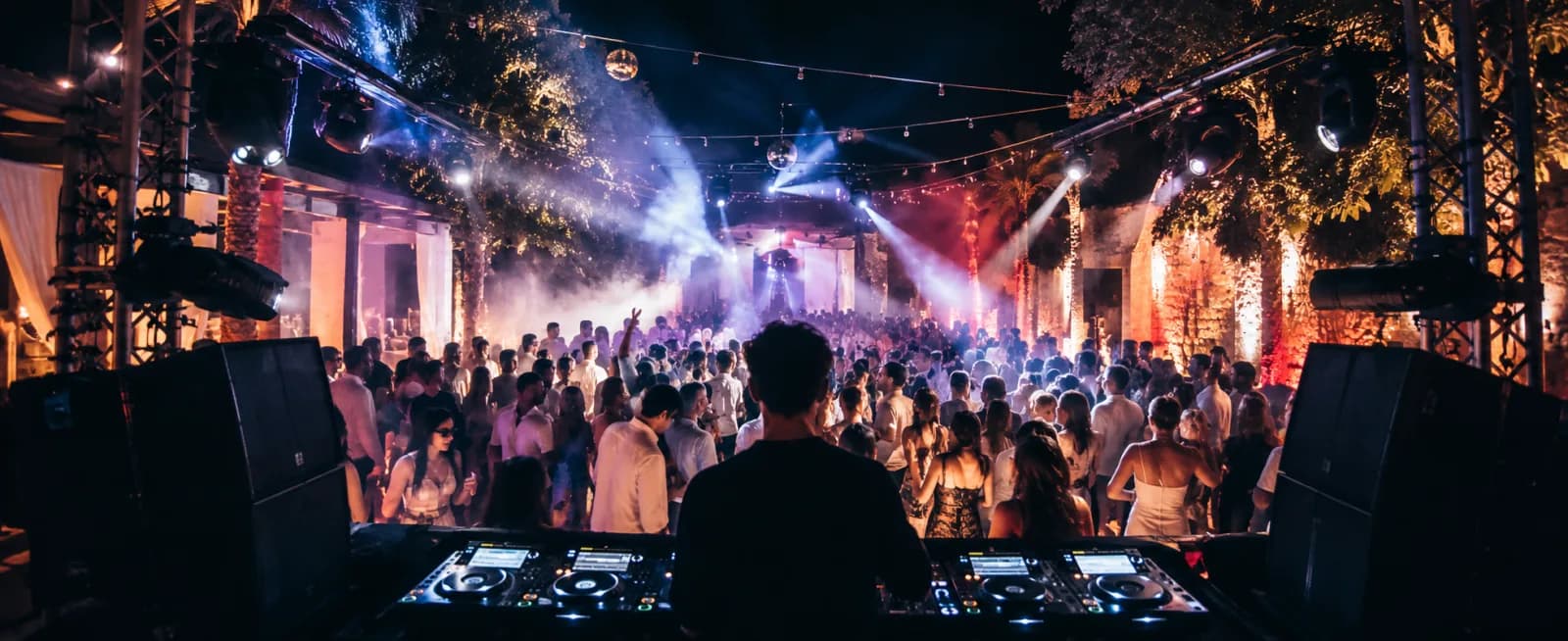 Vista desde la cabina del DJ hacia la pista de baile al aire libre iluminada, de la web existente de Mallorca DJs